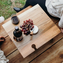 Folding Wine Table The Keepsake Folding Wine Table is a luxurious and high-quality accessory that is perfect for wine lovers. Made from premium acacia wood, it features two holding slots for wine glasses and a slot suited for any wine bottle. 