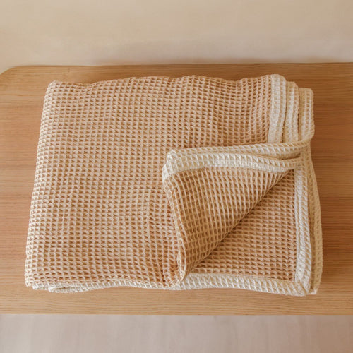 AKIIKO - LATTE PIQUE WAFFLE THROW WITH NATURAL BORDER. INTRODUCING OUR “AKIIKO” RANGE. MADE FROM SOFT, HIGH-QUALITY FABRIC, THIS THROW FEATURES A CLASSIC WAFFLE WEAVE PATTERN AND A NATURAL BORDER FOR A TOUCH OF ELEGANCE.