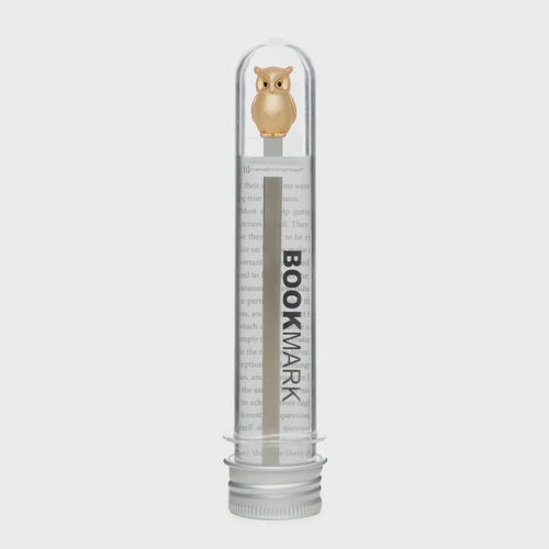 Clear cylindrical container with metal owl shaped bookmark inside.