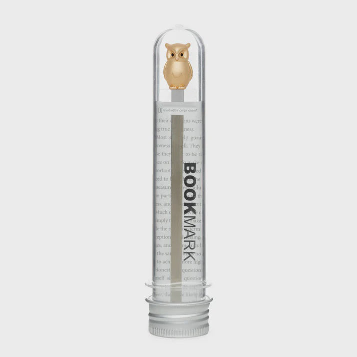 Clear cylindrical container with metal owl shaped bookmark inside.