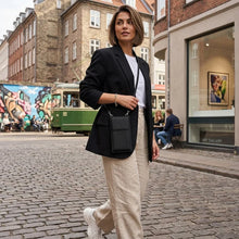Woman walking on street with black phone/wallet bag cross body.
