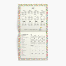 A vertical 2027 planner page spread showing a pastel multicolor confetti border, monthly calendar grids, and printable sections including important dates and 2026 dates, photographed on a light gray background.